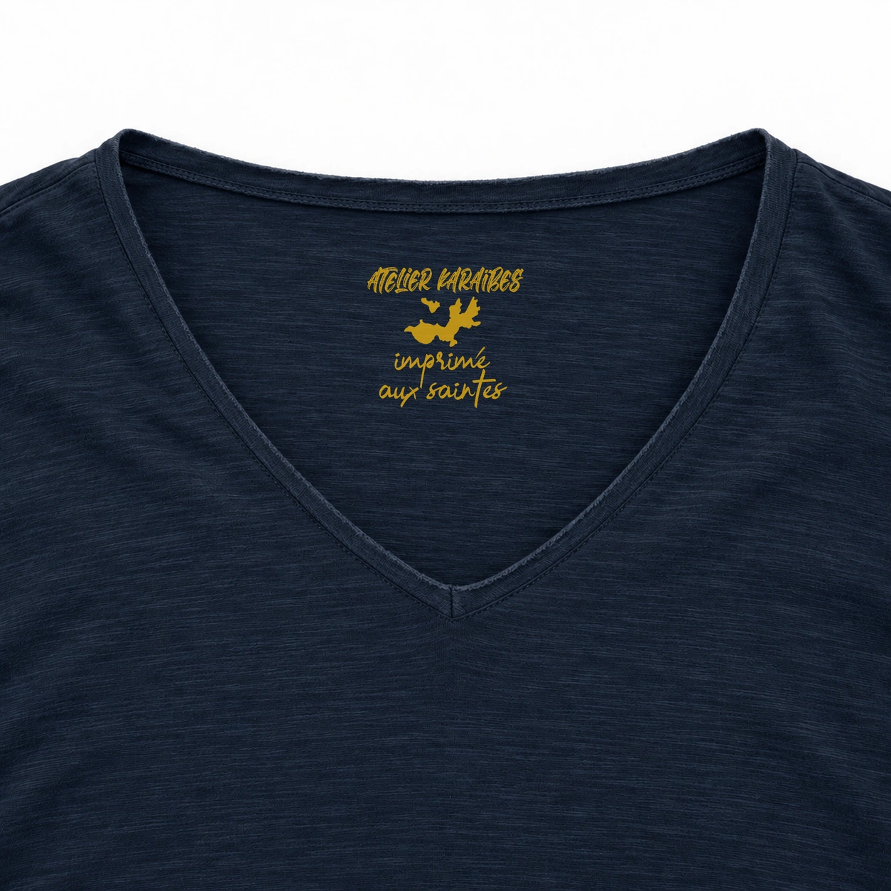 Étiquette intérieure Atelier Karaïbes « imprimé aux Saintes » en jaune moutarde sur le T-shirt col V Navy