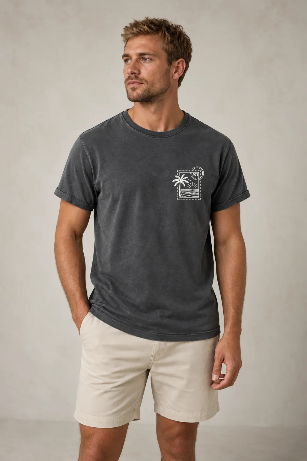 T-shirt vieilli homme gris anthracite délavé avec un timbre palmier 971 avec mer et soleil imprimé en blanc, porté par un homme en studio dans une lumière naturelle