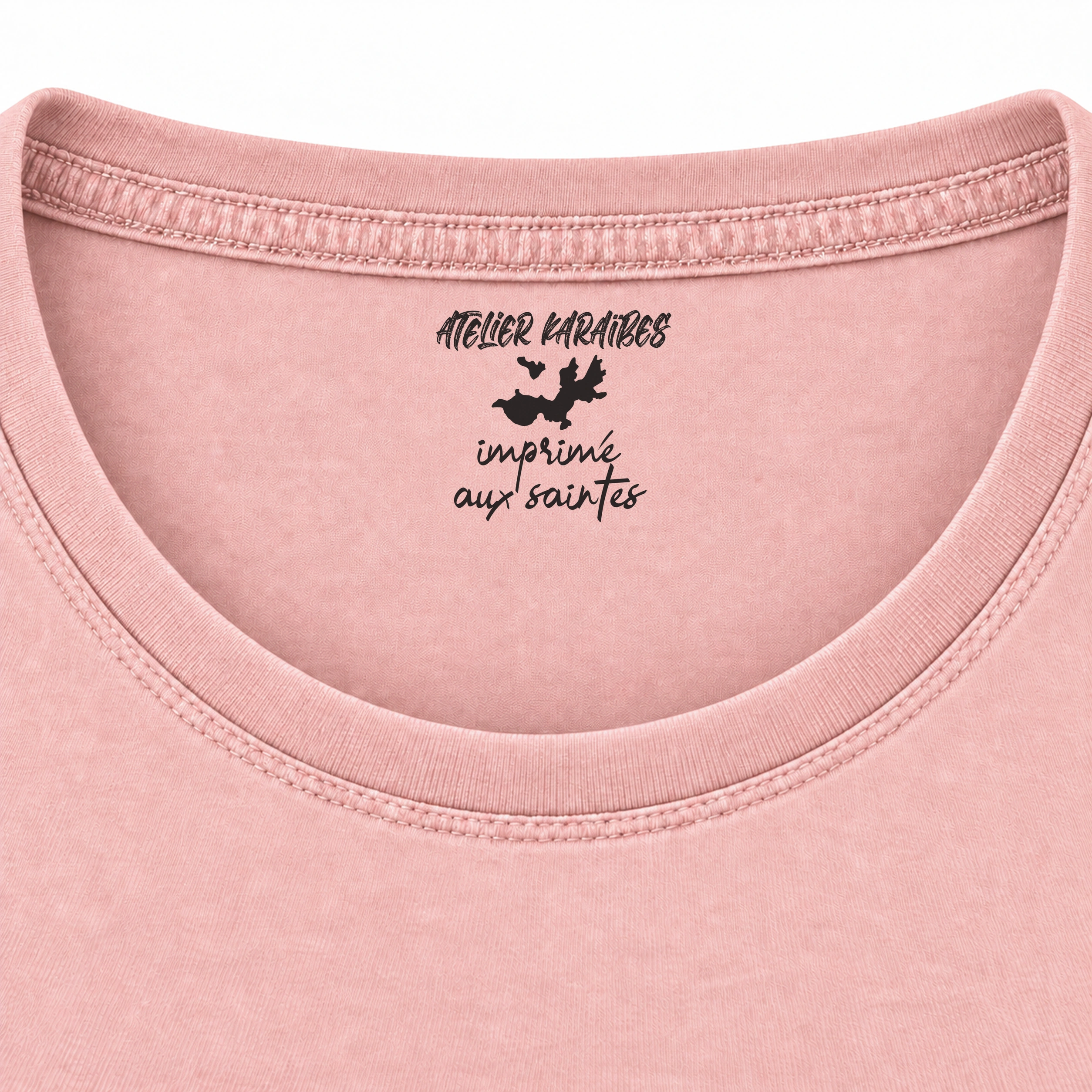 Étiquette intérieure Atelier Karaïbes « imprimé aux Saintes » en noir sur le T-shirt rouloté rose