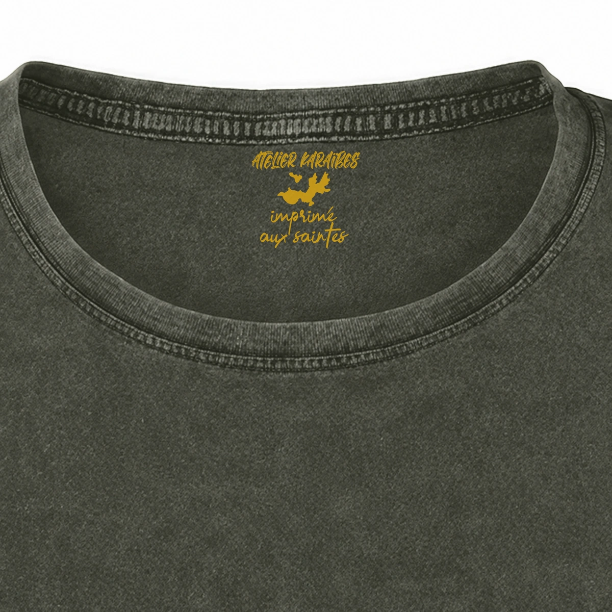 Gros plan de la signature intérieure Atelier Karaïbes imprimée en jaune moutarde sous le col du T-shirt vieilli femme vert militaire foncé délavé