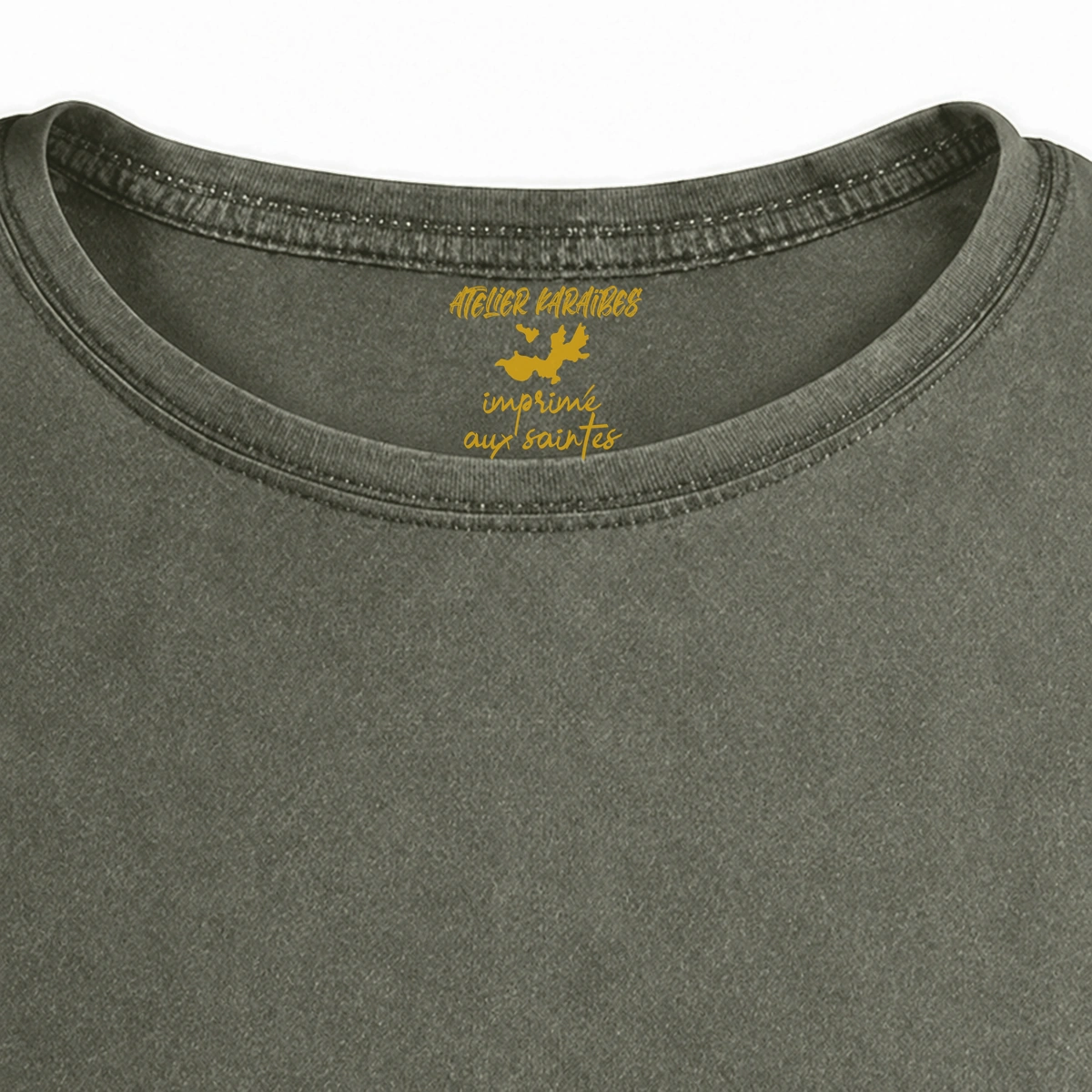 Gros plan de la signature intérieure Atelier Karaïbes imprimée en jaune moutarde sous le col du T-shirt vieilli homme vert militaire foncé délavé